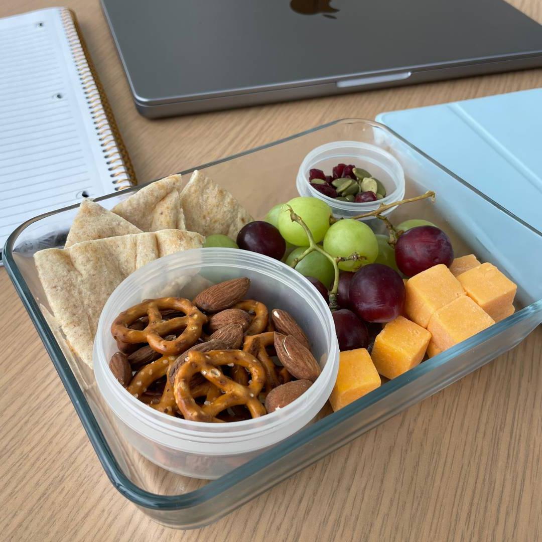 Homemade snack box with fruit, cheese and nuts around study material